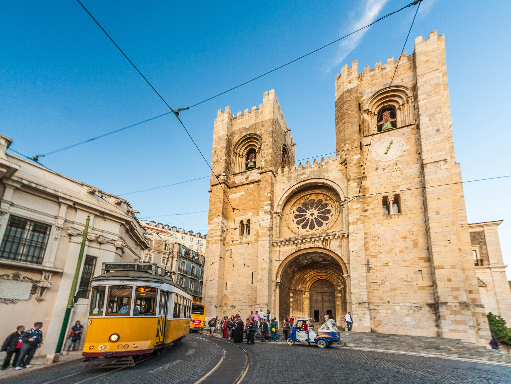 De kathedraal in Lissabon, Portugal, met een gele tram vooraan, die typisch is voor de stad